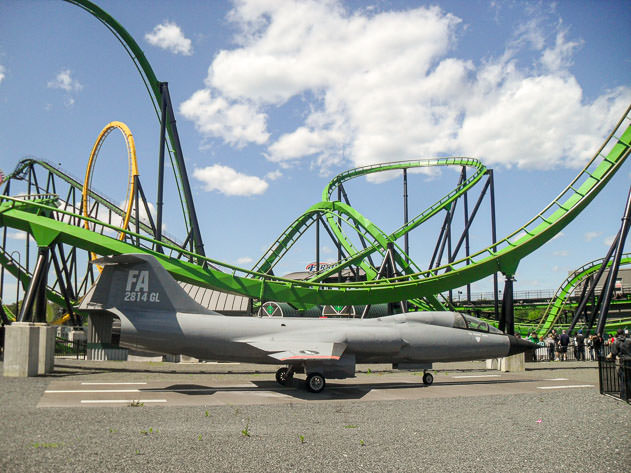 A roller coaster with a military plane next to it