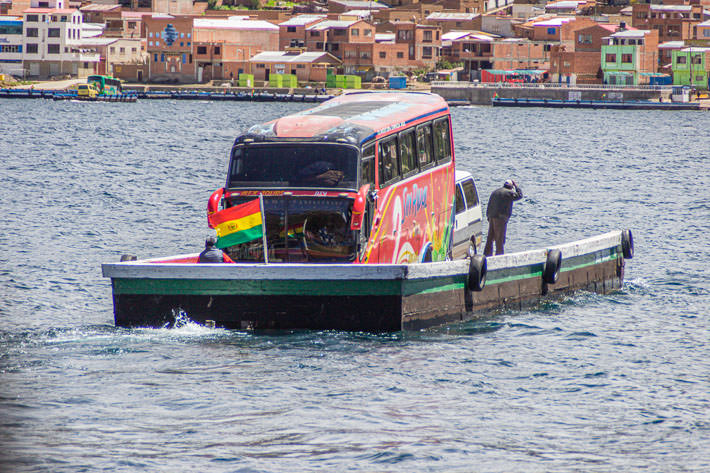 A ferry carries a bus and a van in the strait of Tiquina