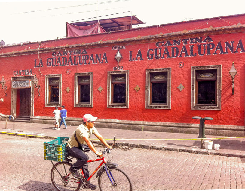 A man rides his bike before a cantina in the bohemian neighborhood of Coyoacán