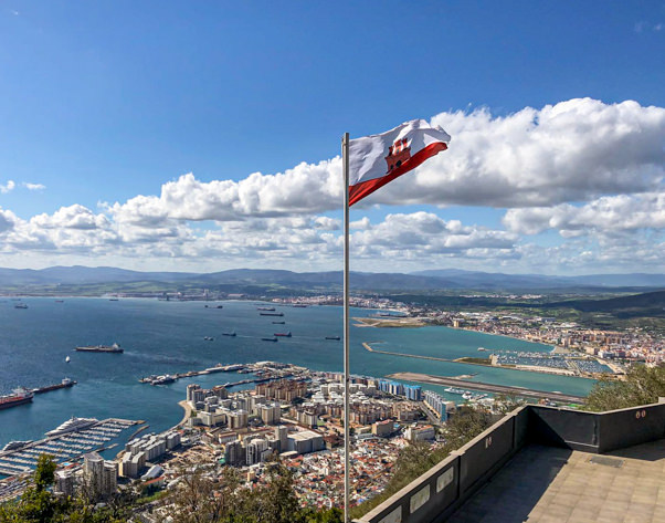 Flag of Gibraltar with the Bay in the background